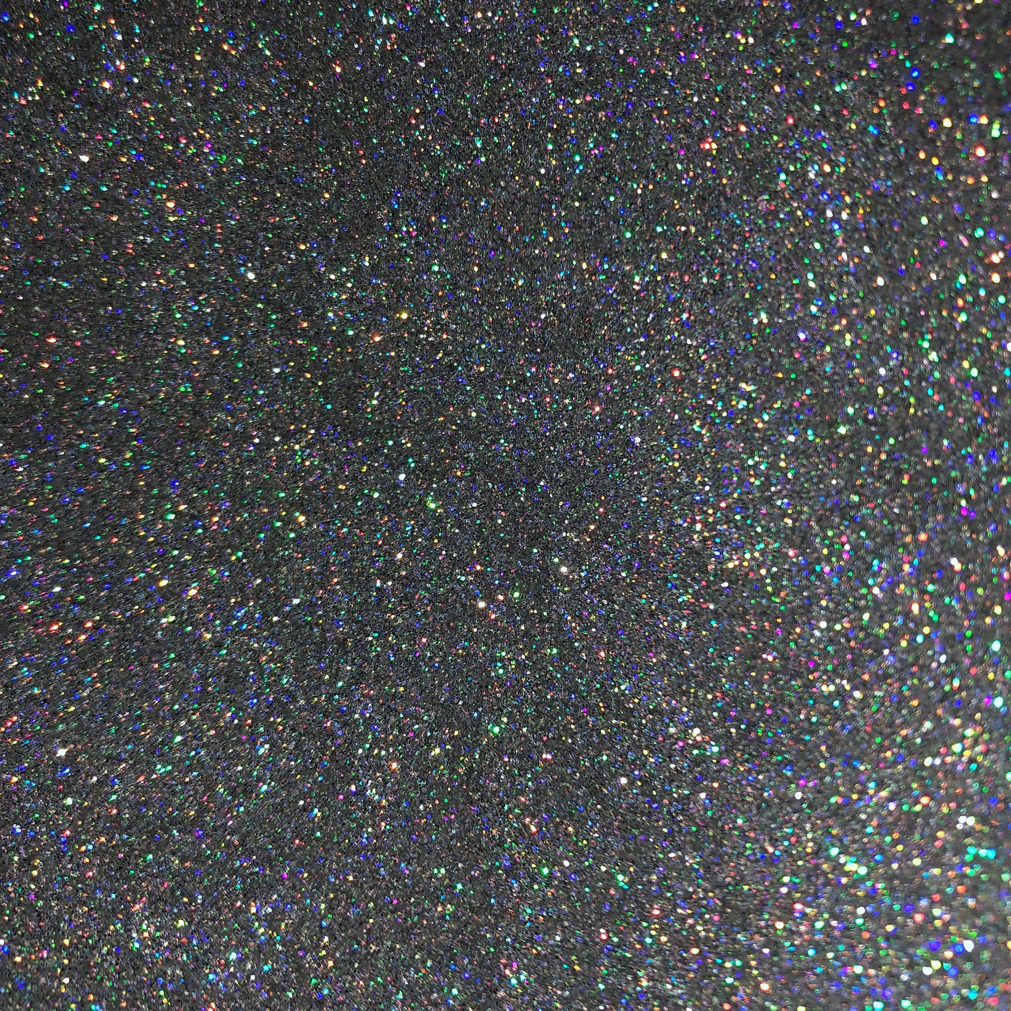 Close-up of holographic silver glitter eyeshadow with reflective shimmer particles in compact pan