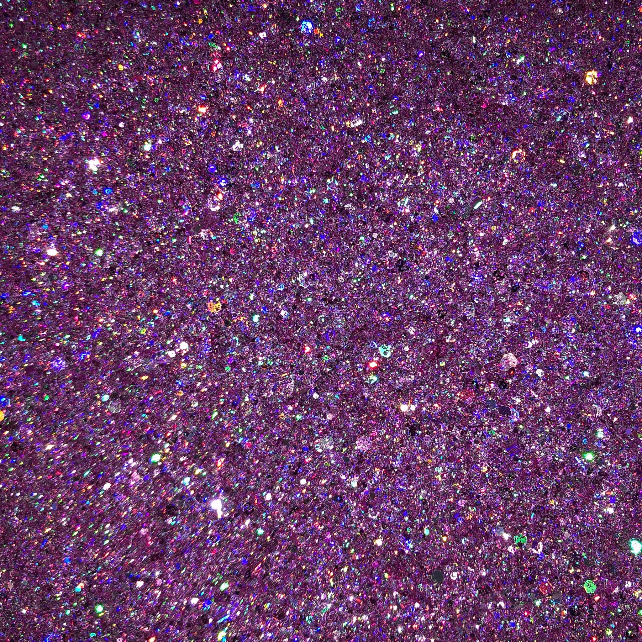 Close-up of vibrant pink and purple glitter eyeshadow palette with shimmering particles catching light