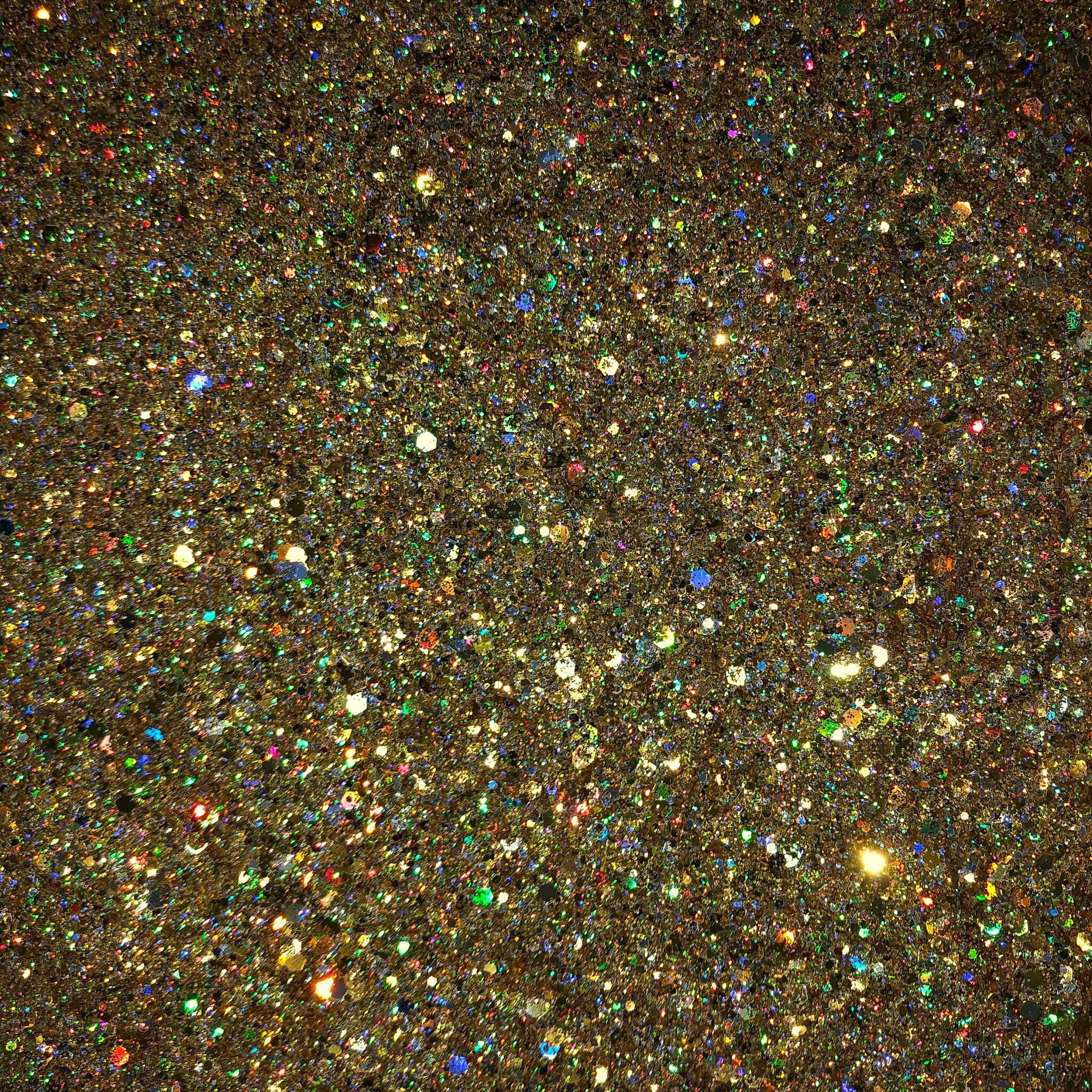 Close-up of True Gold Glitter Eyeshadow pot showing intense metallic shimmer and fine golden sparkles