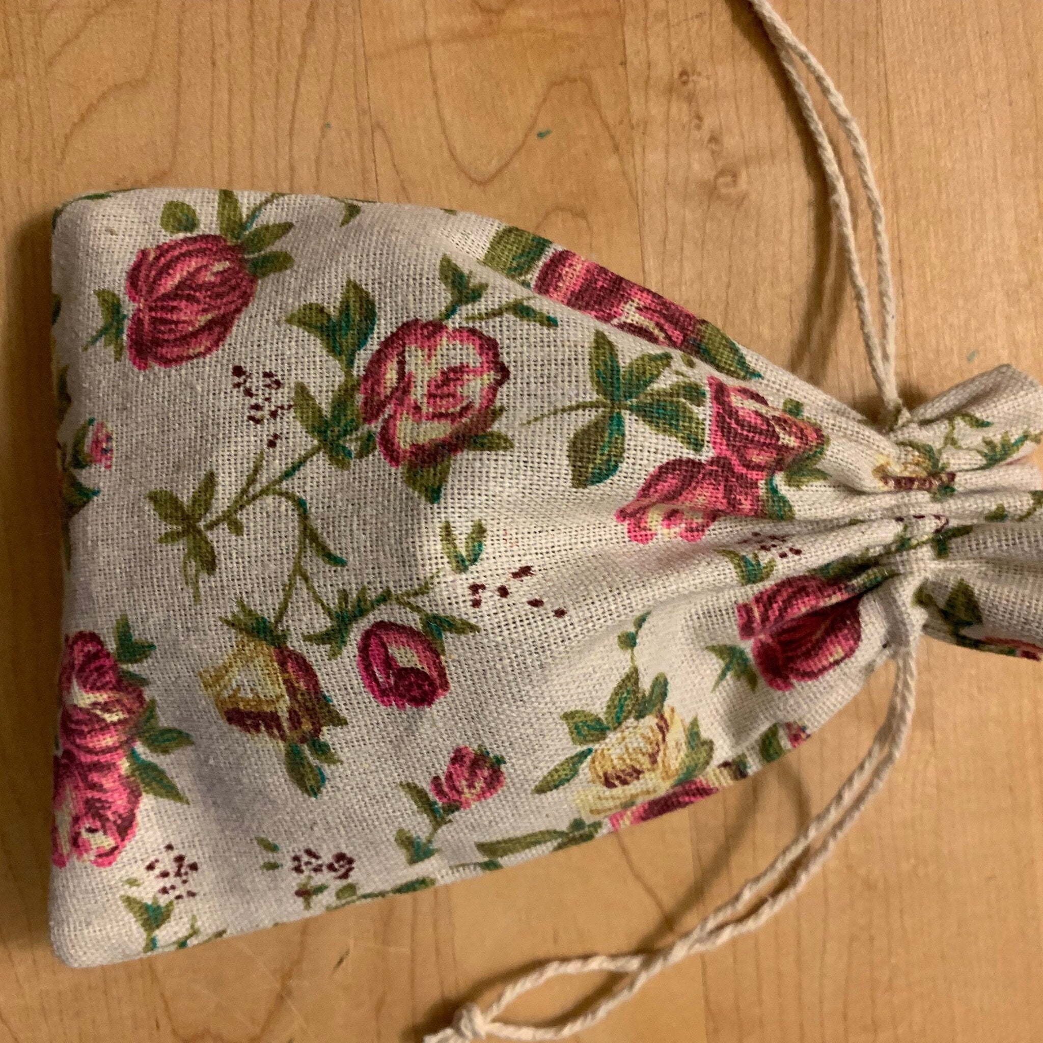 Drawstring bag with floral pattern, beige linen material, and rope tie closure
