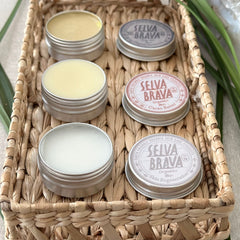Skin care products in silver tins with yellow, white, and brown contents, displayed in a woven basket, SELVA BRAVA branding visible