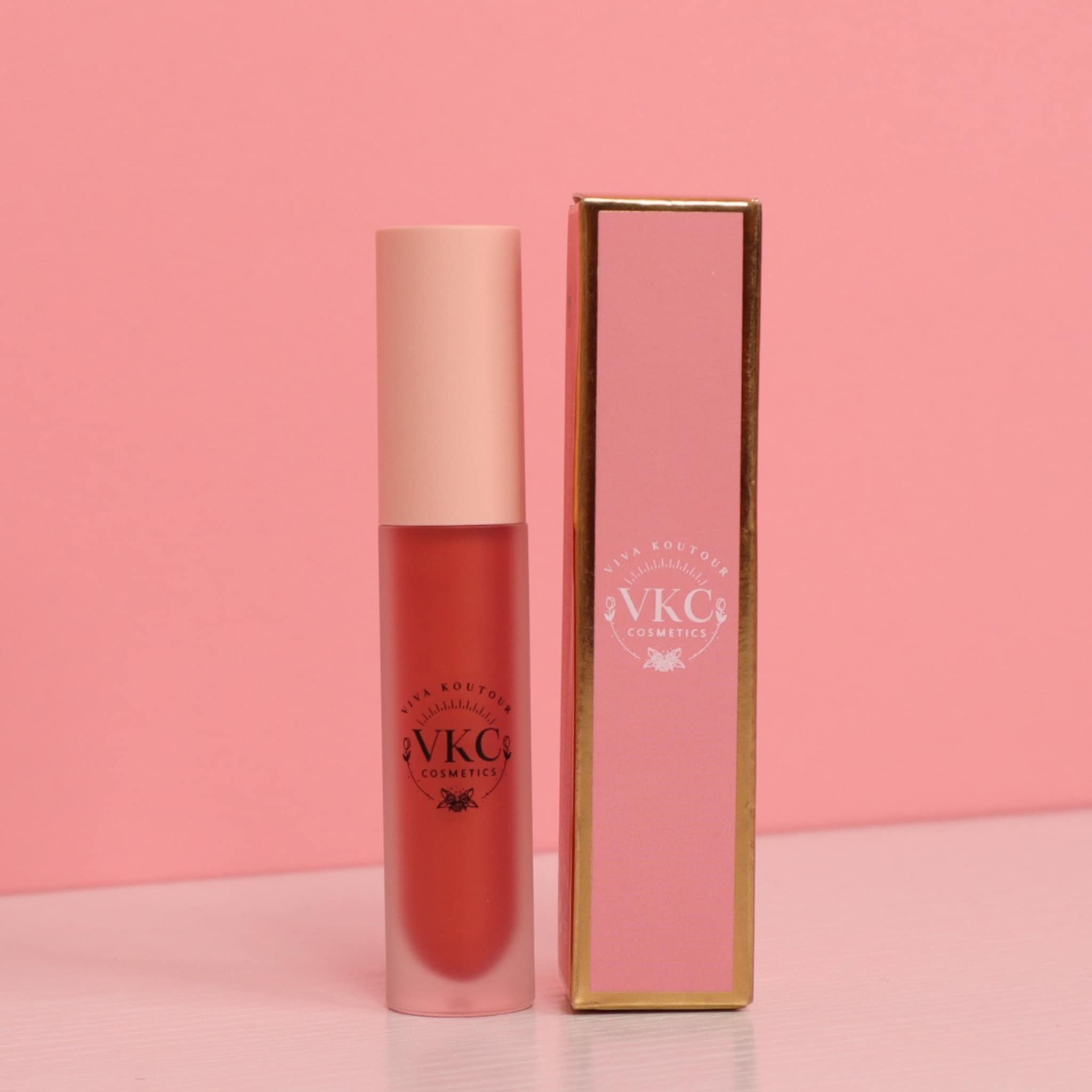 Lip gloss tube with matte finish, peach cap, and VKC Cosmetics branding on pink box