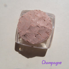 Close-up of loose mineral eyeshadow in frosty golden champagne with shimmering beige-brown tones