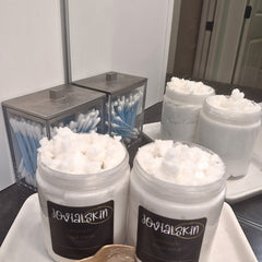 Sugar scrub in white jars with JovialSkin labels, cotton swabs in clear containers on a tray