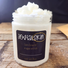 Sugar scrub in a clear jar with white scrub, black label, and JovialSkin brand name visible.