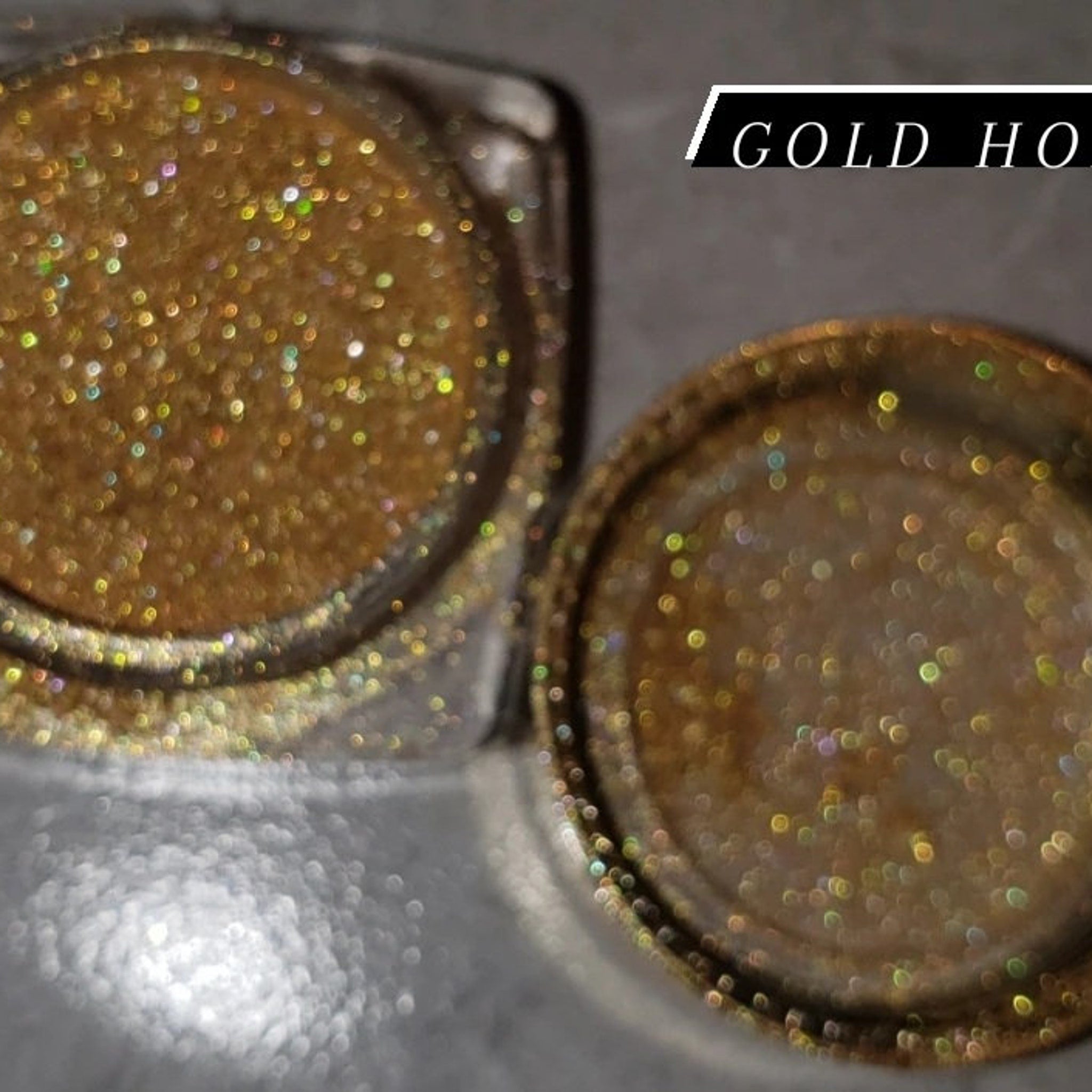 Close-up of loose shimmering gold glitter eye shadow with fine sparkles, scattered on a white surface.