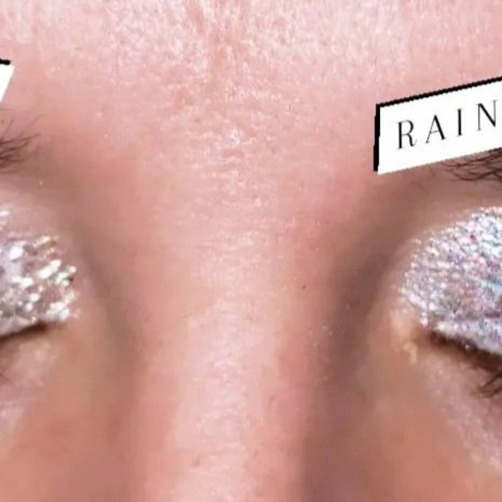Side view of shimmering loose glitter eye shadow in a sleek transparent jar with gold lid, showcasing fine sparkle texture