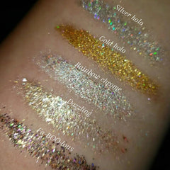 Side view of shimmering loose glitter eye shadow pot with iridescent particles catching light