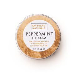 Lip balm in round metal tin with tan textured border and white label, Rayburn's Naturals brand