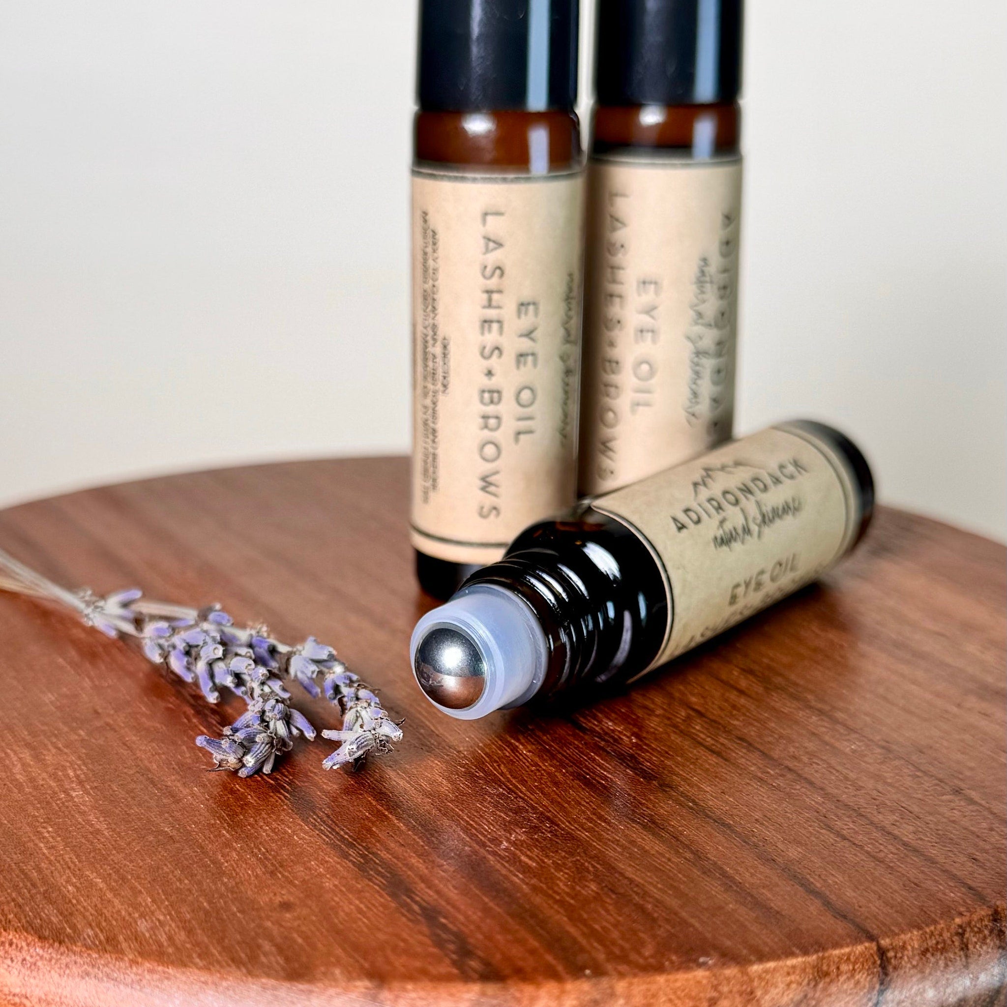 Eye oil bottles with brown glass, black caps, and silver rollerball applicator, with lavender