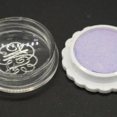 Purple eyeshadow compact with white scalloped edge and clear container with logo detail