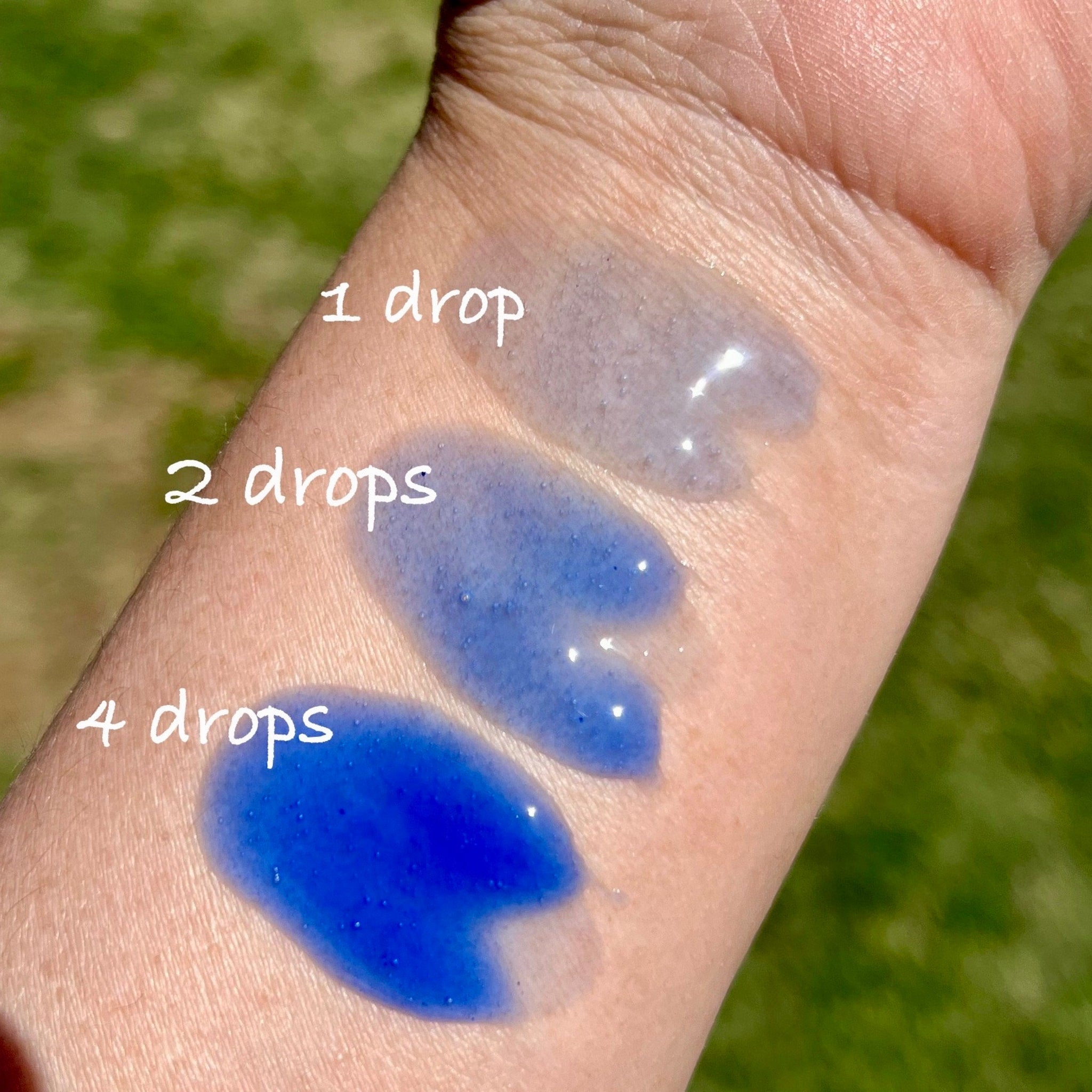 Blue liquid drops on skin, showing color variations with quantity, in a close-up shot