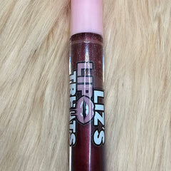 Lip gloss tube with pink cap, dark red glitter, and Liz's Lip Treats branding on fur background