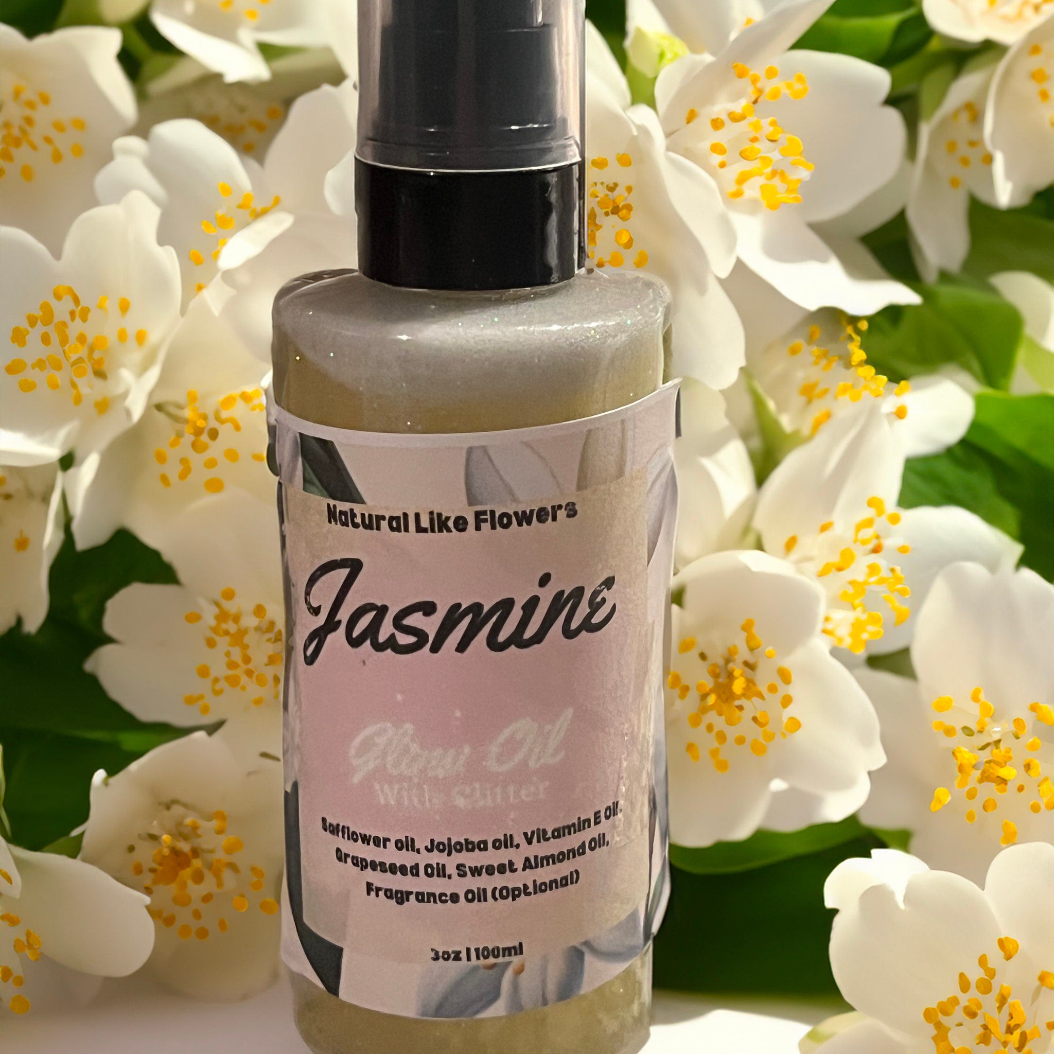 Jasmine glow oil bottle, clear glass, black cap, with "Natural Like Flowers" label, white flowers background