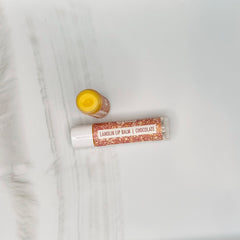 Lanolin lip balm with white tube, brown glitter pattern, and yellow balm inside