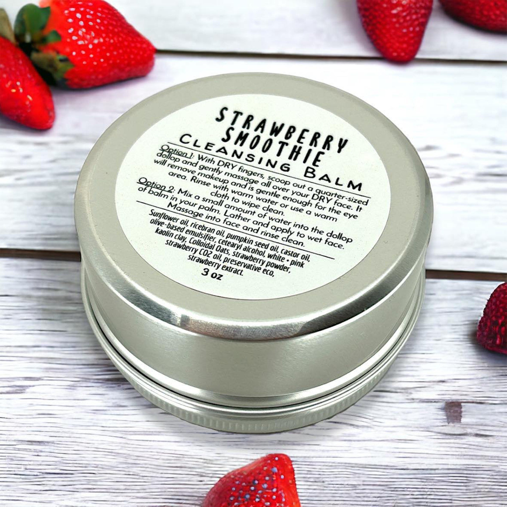 Cleansing balm tin, silver metal container with white label, "Strawberry Smoothie" text visible