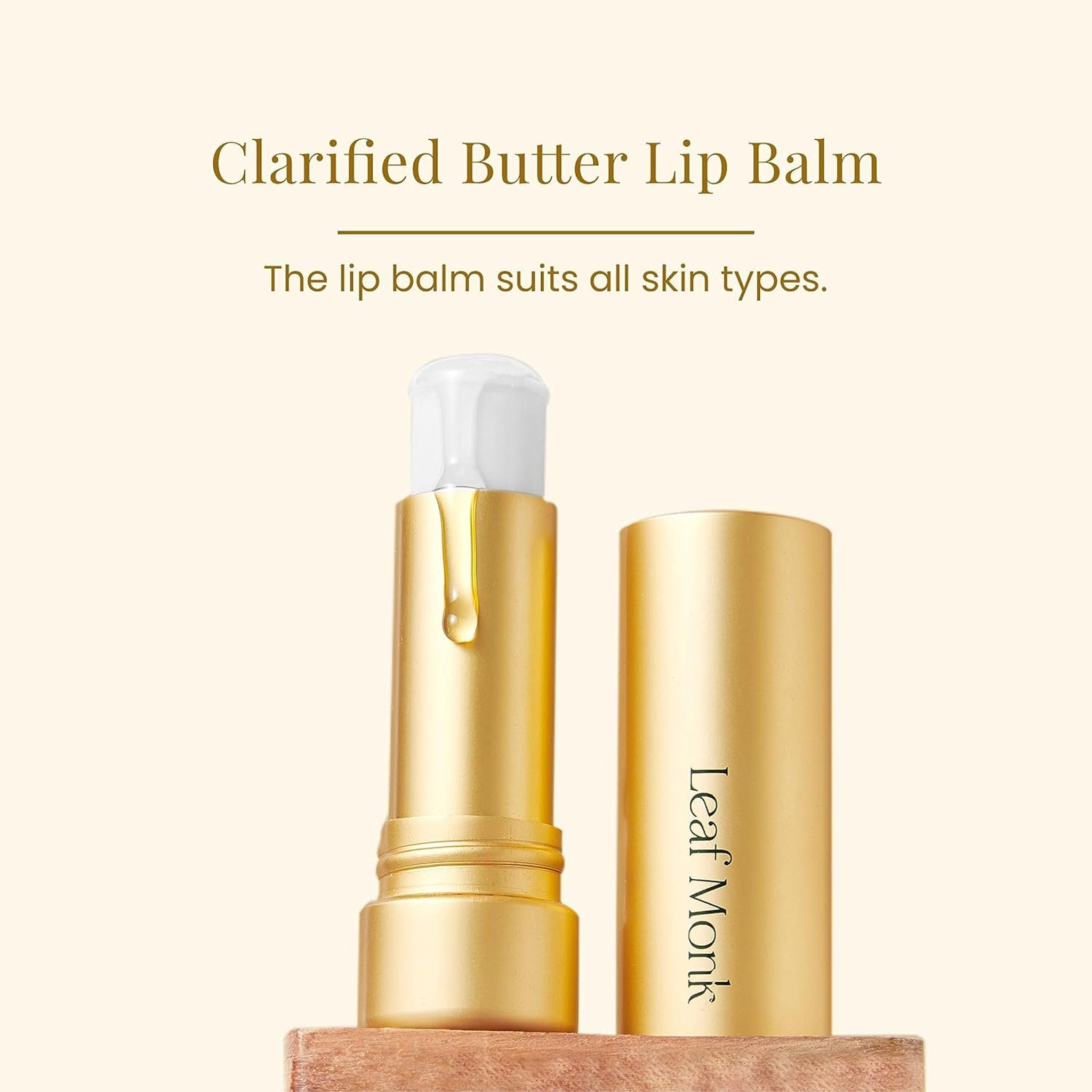 Lip balm in gold tube with white cap and Leaf Monk branding, on wooden surface