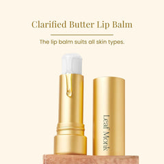 Lip balm in gold tube with white cap and Leaf Monk branding, on wooden surface