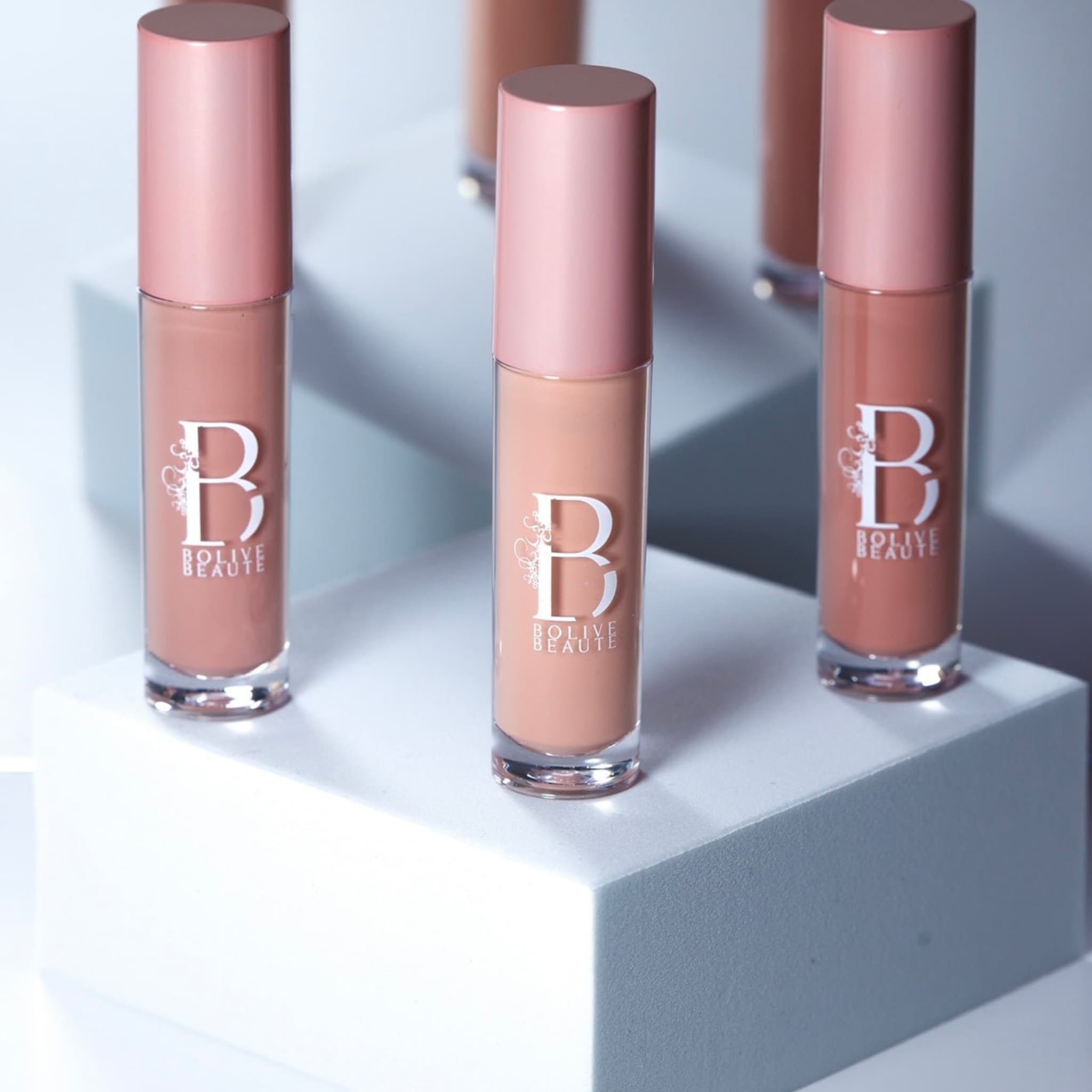 Lip gloss tubes with pink caps, Bolive Beaut logo, and light brown liquid inside