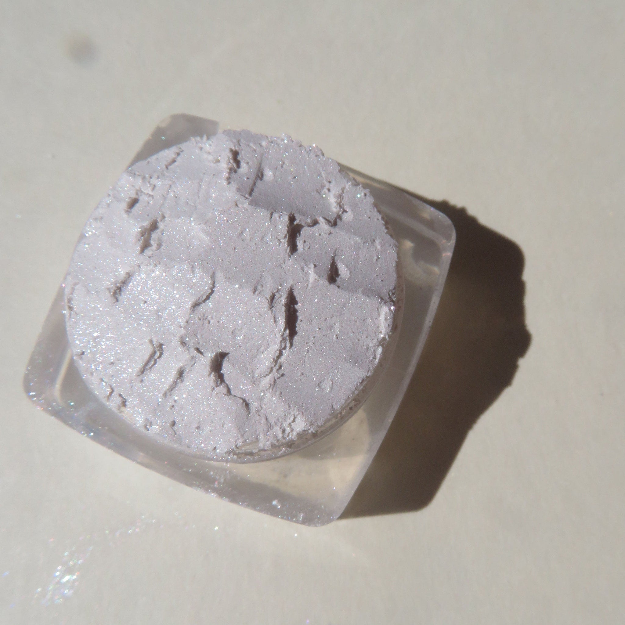 Hand applying soft white shimmery mineral eyeshadow with fingertip for a glowing highlight effect