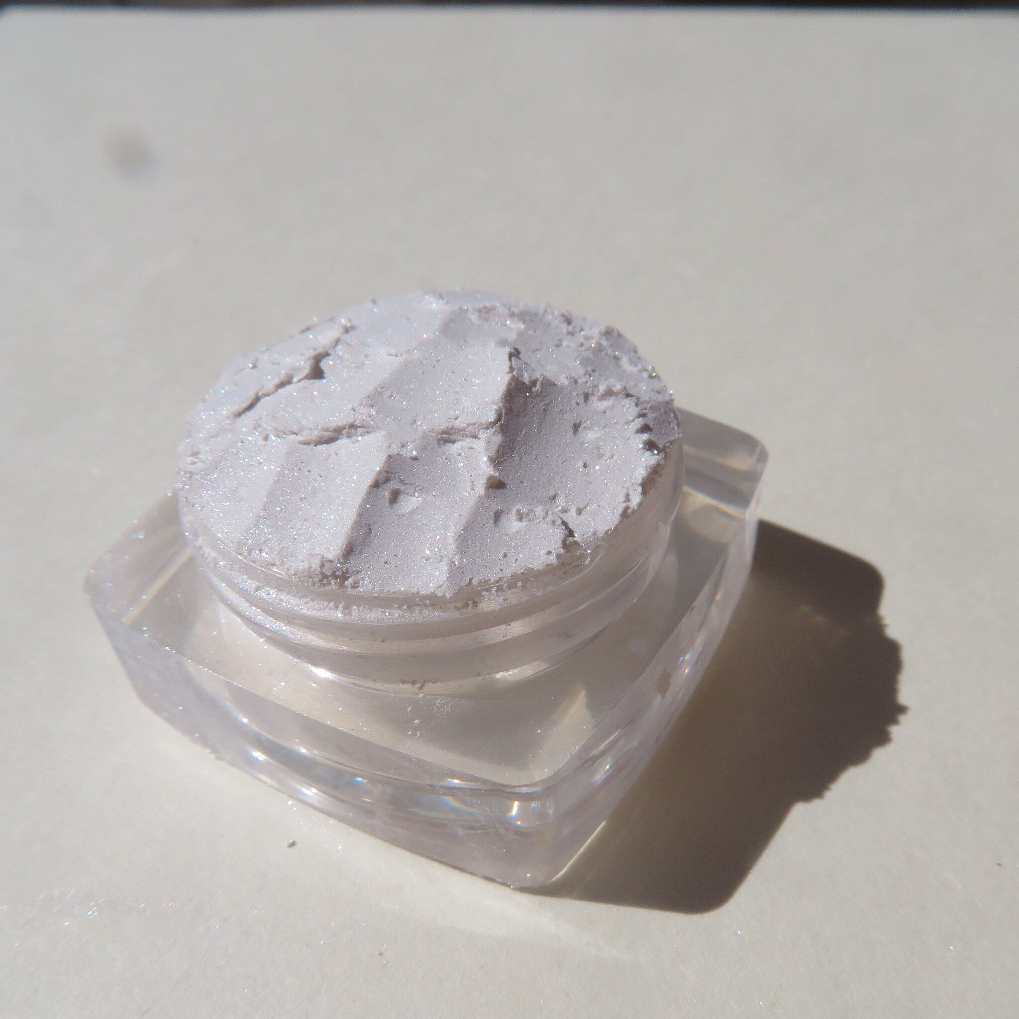 Close-up of loose shimmering white mineral eyeshadow powder with vegan formula, highlighting fine texture and pearlescent finish