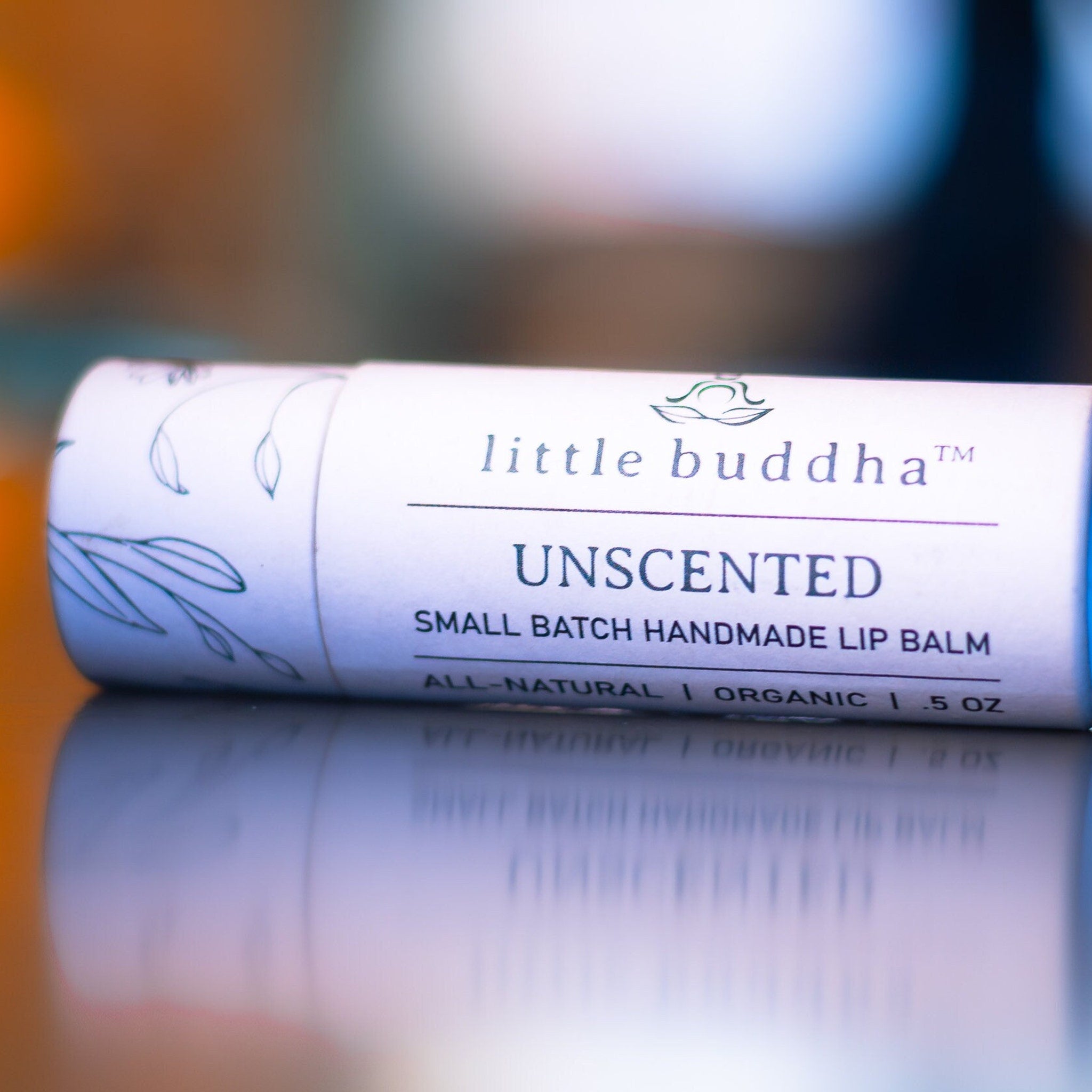 Lip balm tube with white paper, blue text, and "little buddha" brand name visible