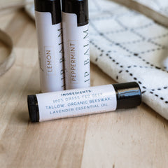 Lip balm tubes with white labels, black caps, and text on wooden surface