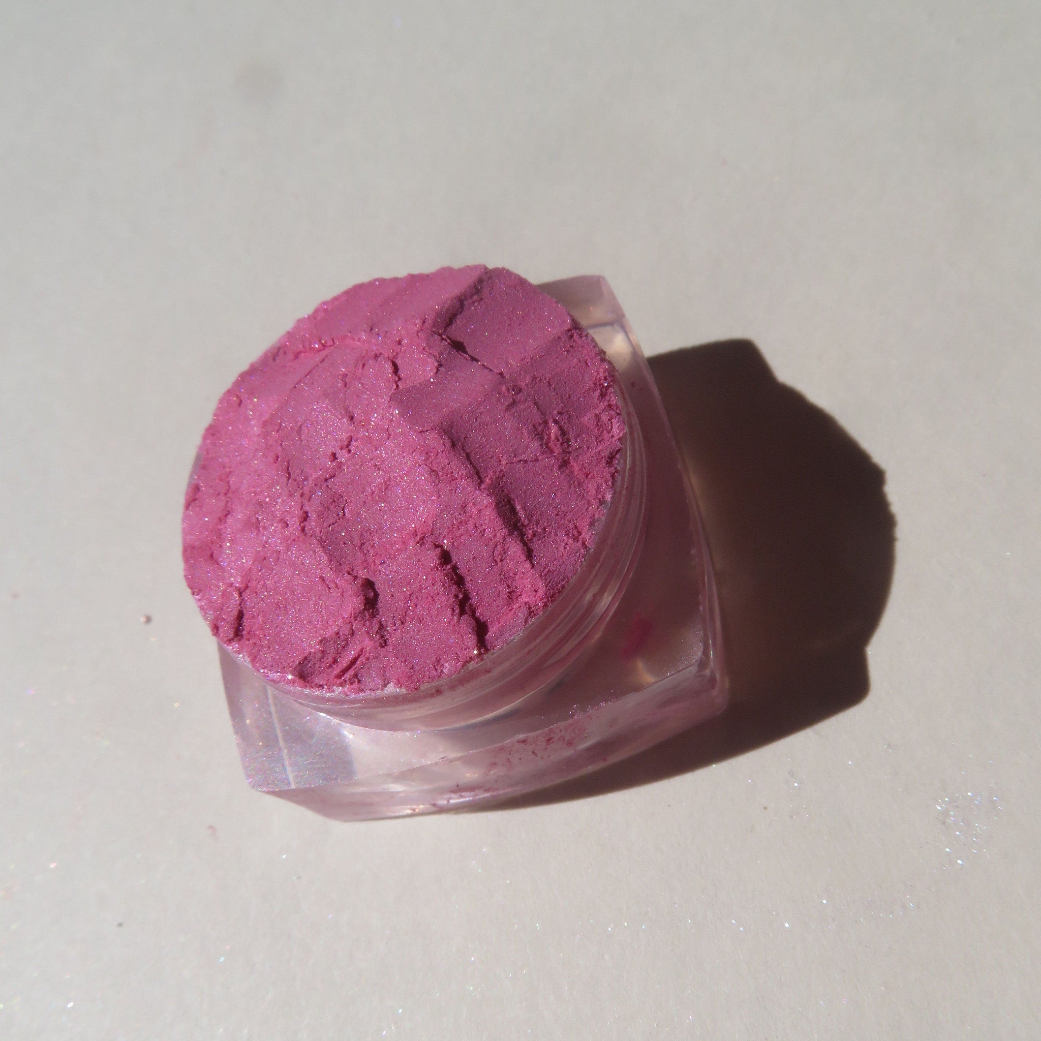 Hand applying soft sheer pink loose mineral eyeshadow with fingertip for a subtle blush effect