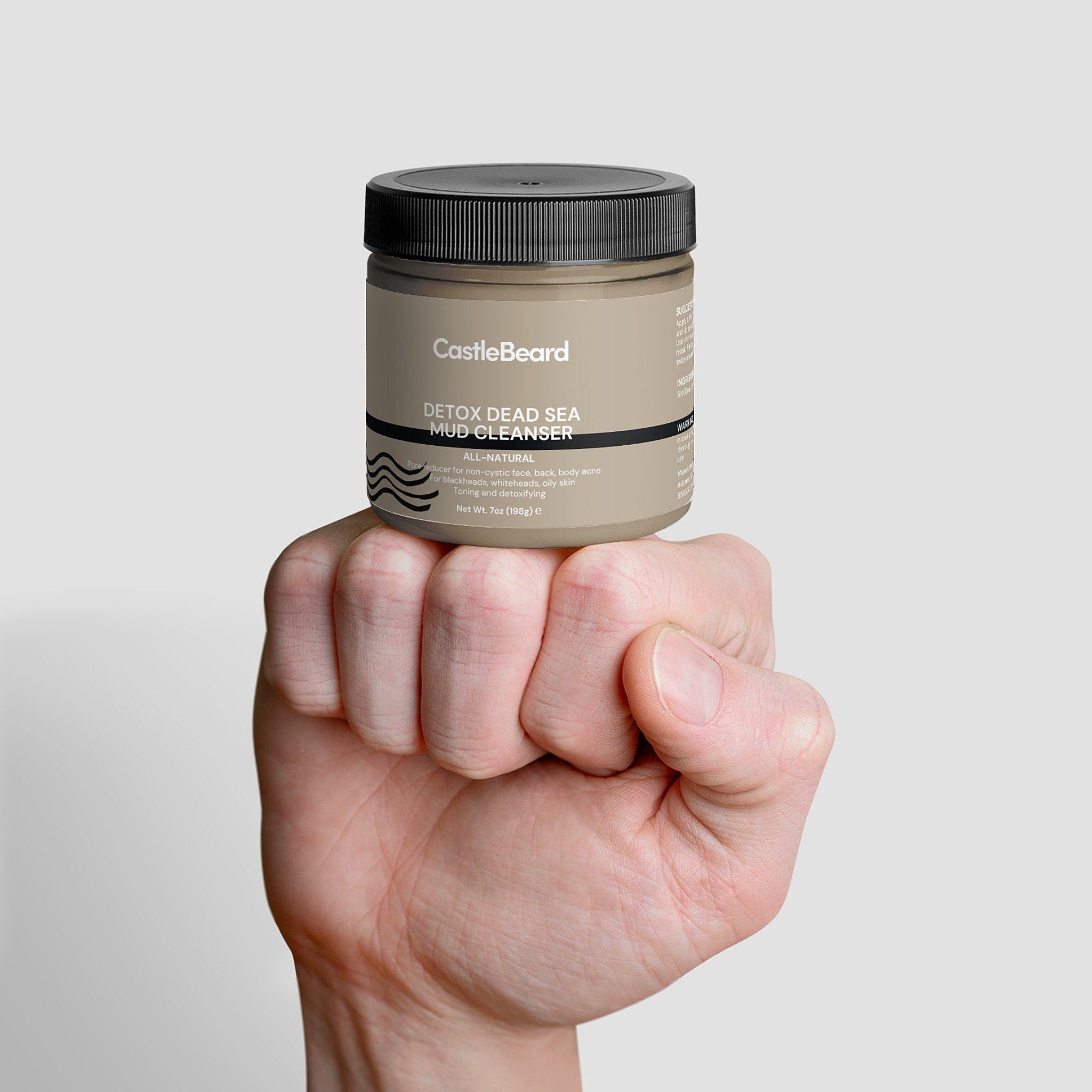 Mud cleanser jar with black lid, tan label, and CastleBeard brand, held in hand