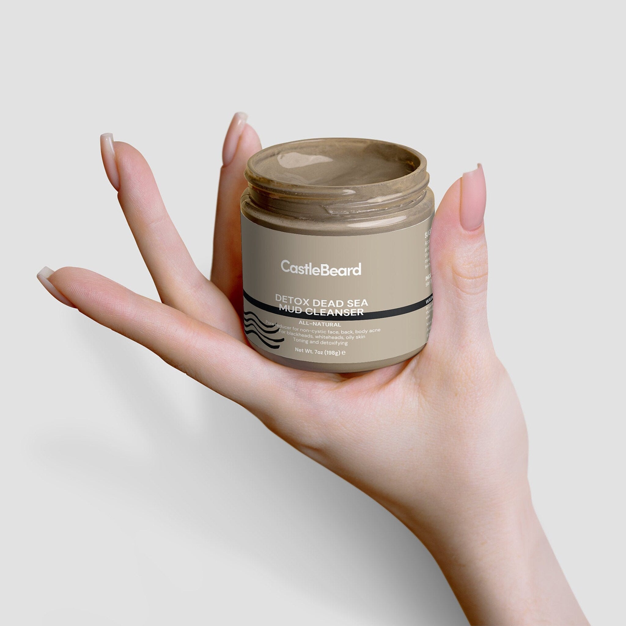 Mud cleanser jar with tan contents, beige label, and held in hand by fingers