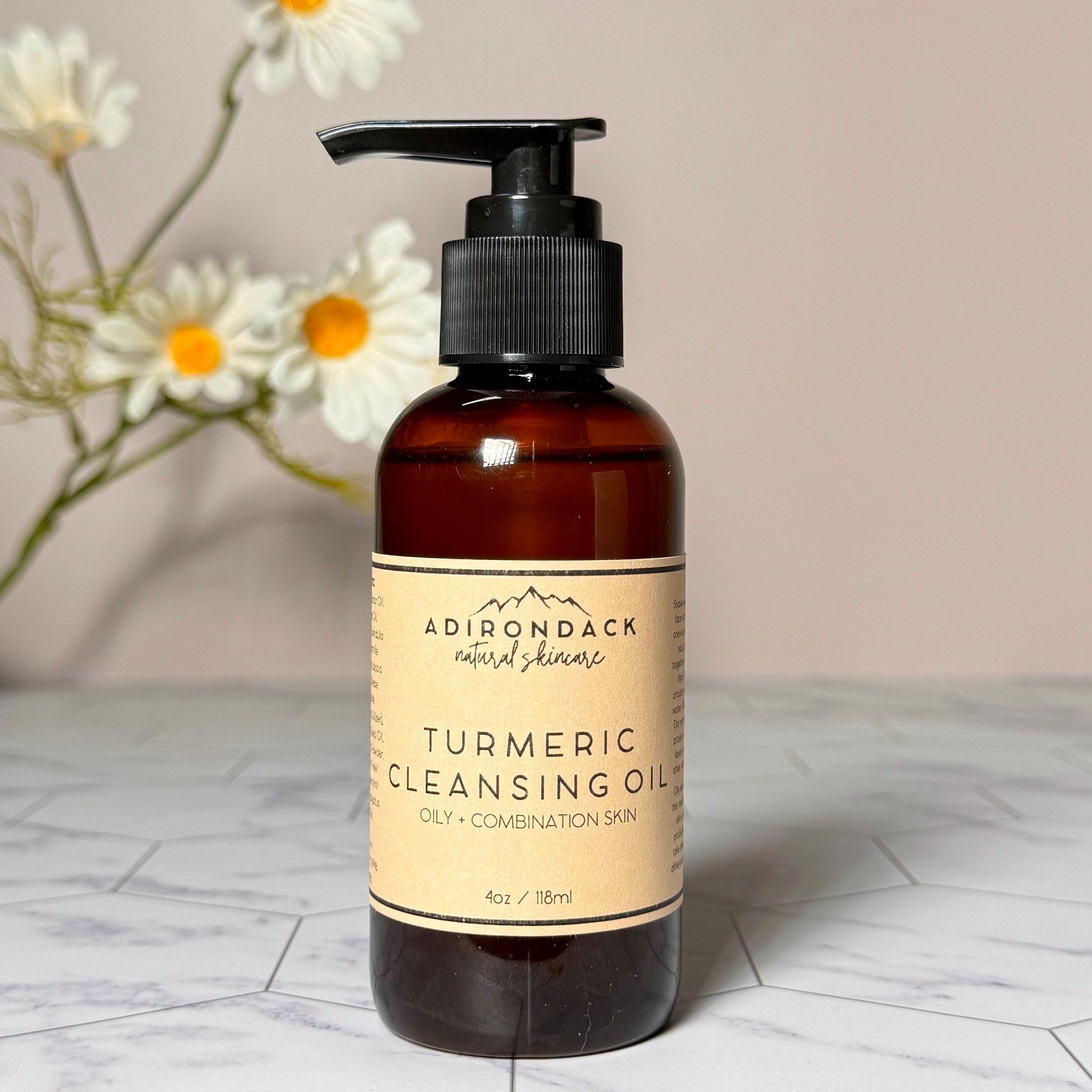 Cleansing oil bottle with black pump, brown glass, and tan label with text "Adirondack