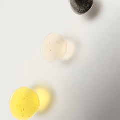 Skincare drops of yellow, white, and gray colors on white background, close-up view