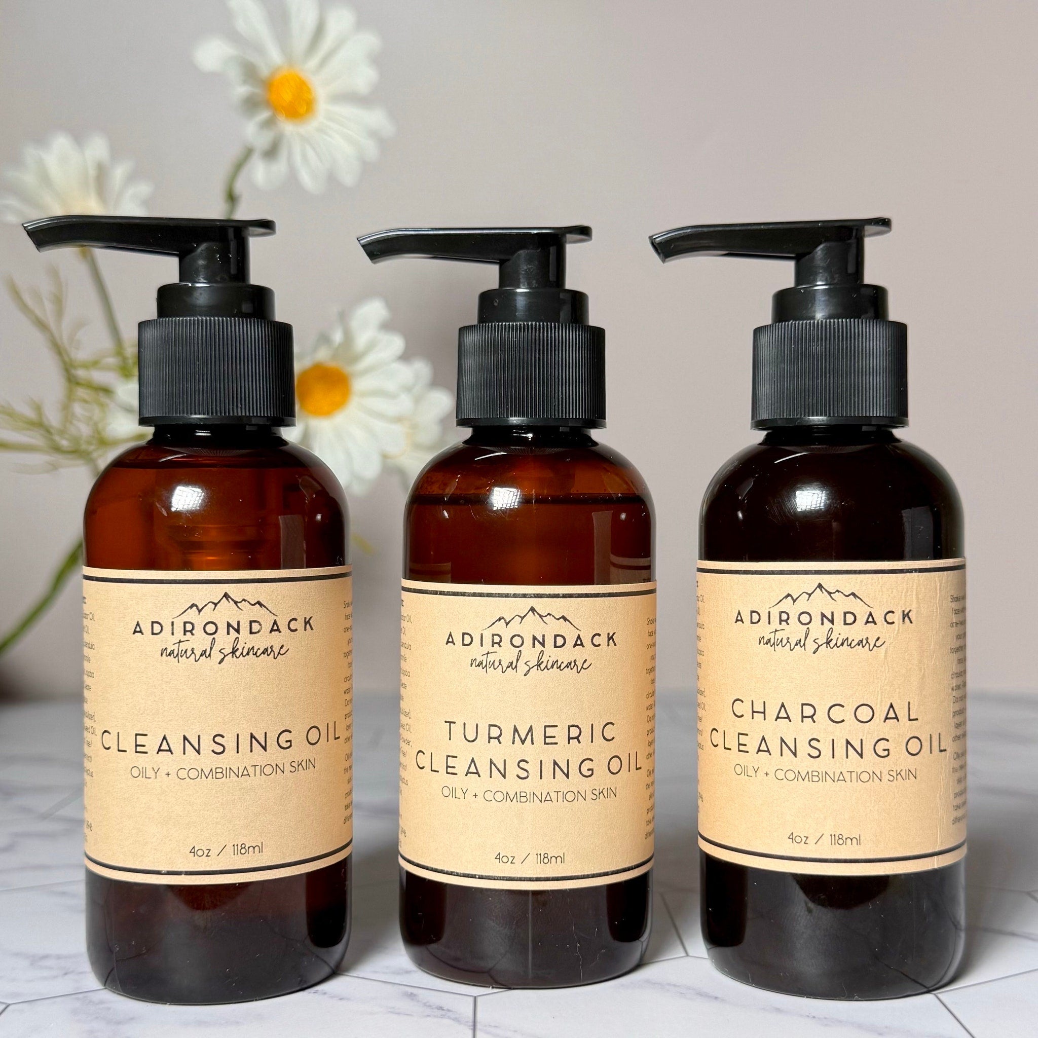 Cleansing oil bottles with black pump tops, amber glass, and tan labels with Adirondack text
