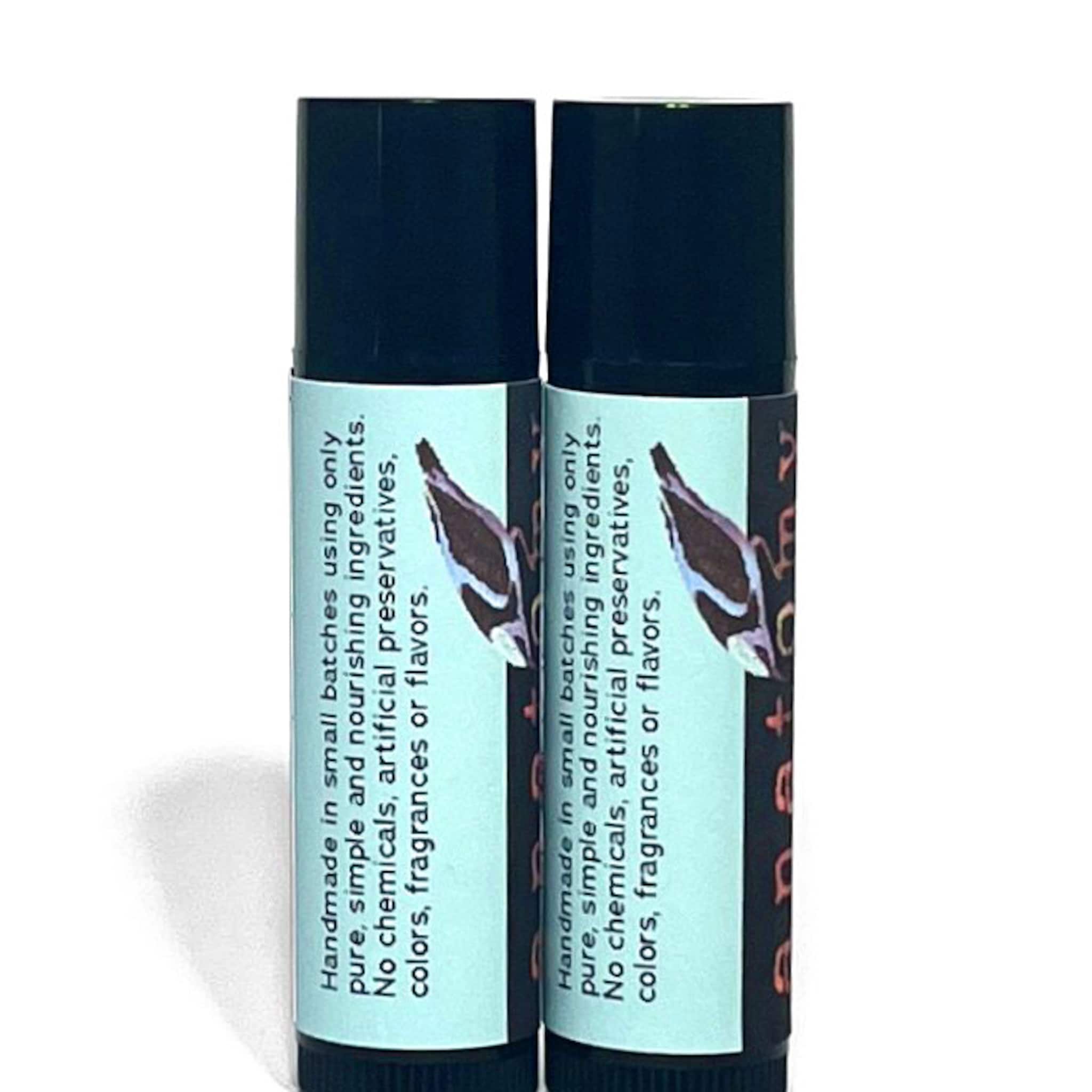 Lip balm tubes with black caps and light blue labels with text, side view