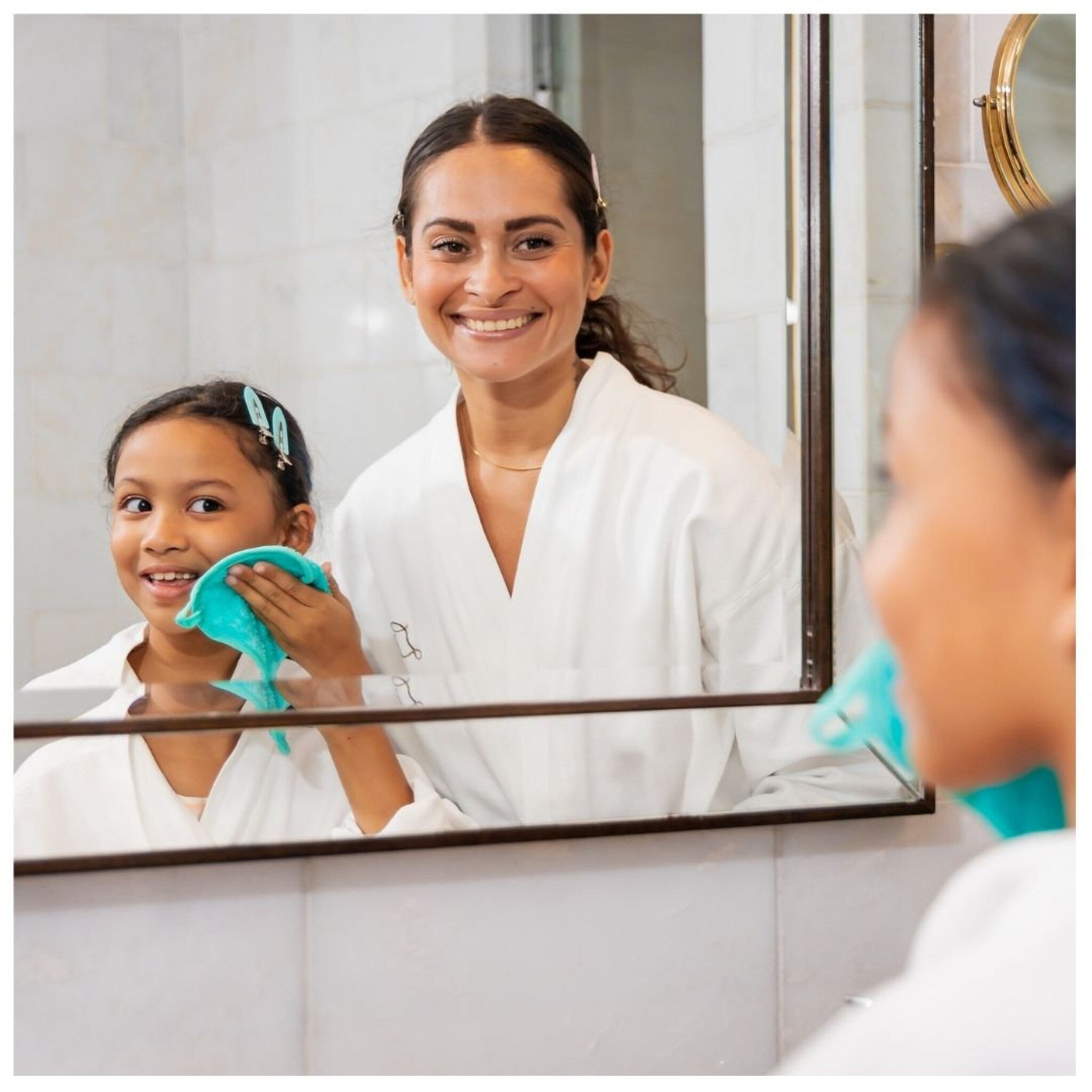 Facial cleansing cloth, turquoise, soft, being used by a child in the mirror