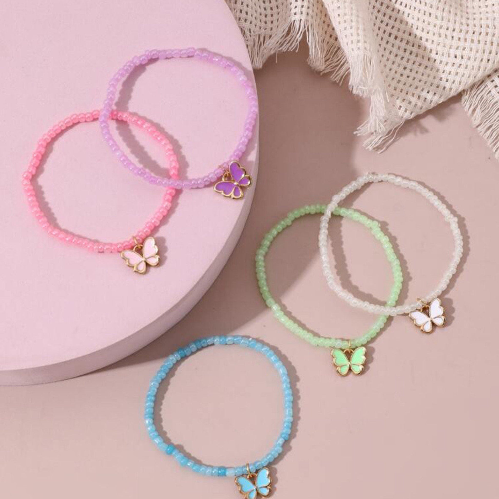 Beaded bracelets with butterfly charms in pink, purple, green, white, and blue colors