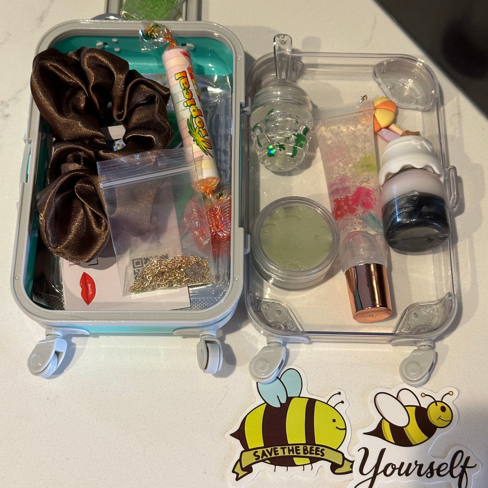 Scrunchie and lip gloss set with brown scrunchie, clear container, and stickers on white surface
