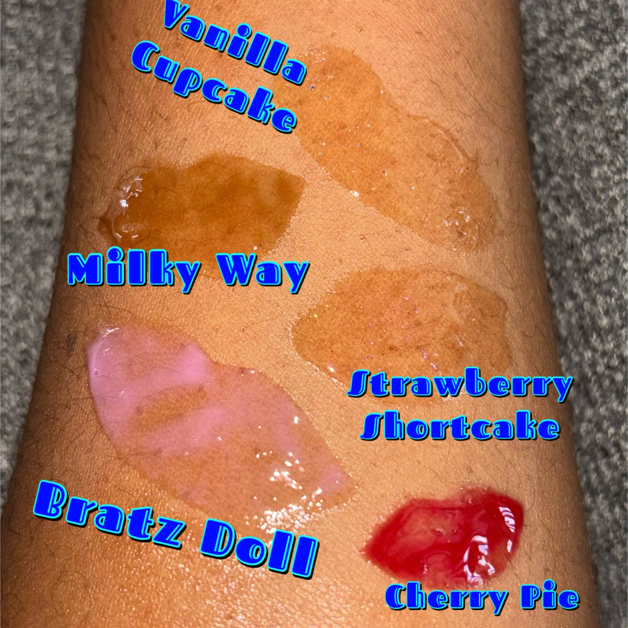 Lip gloss swatches, various colors including pink, brown, and red, applied on skin, showing different shades
