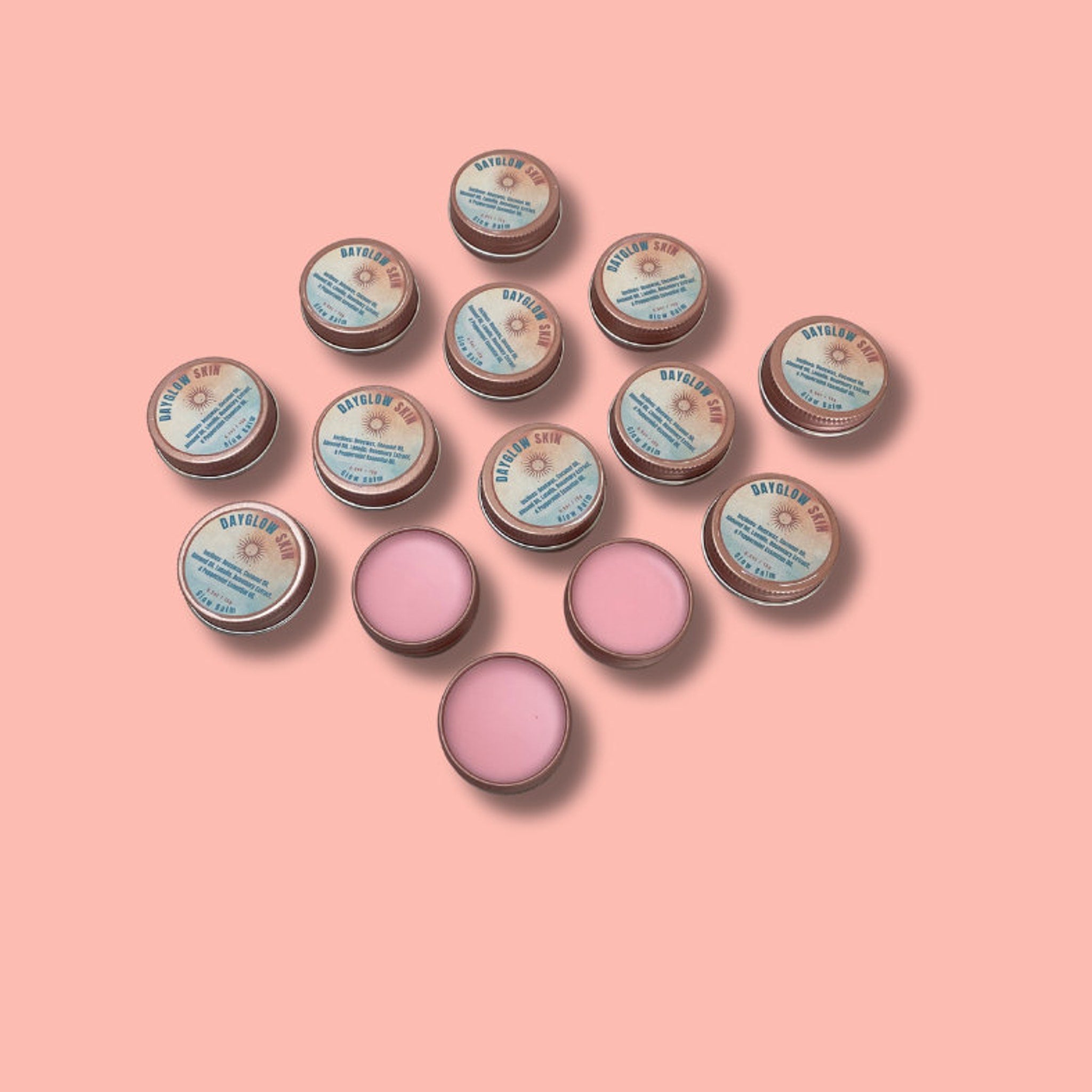 Lip balm tins with DAYGLOW SKIN text, pink balm, and metal tins on a pink background