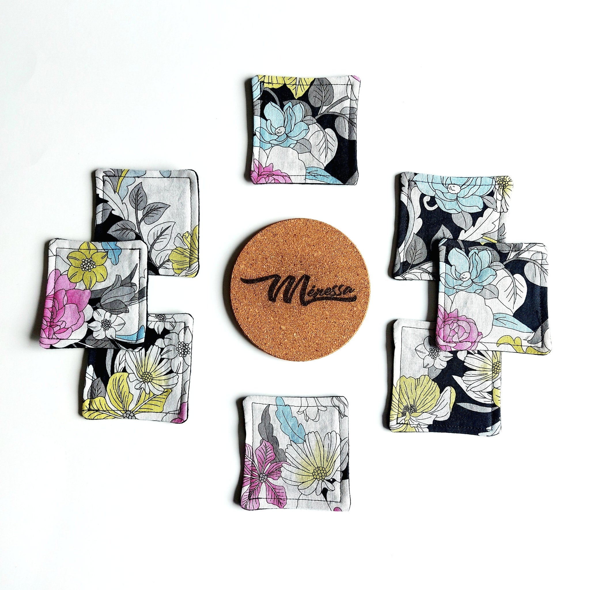 Coasters with floral pattern, black trim, and cork coaster with "Minessa" logo
