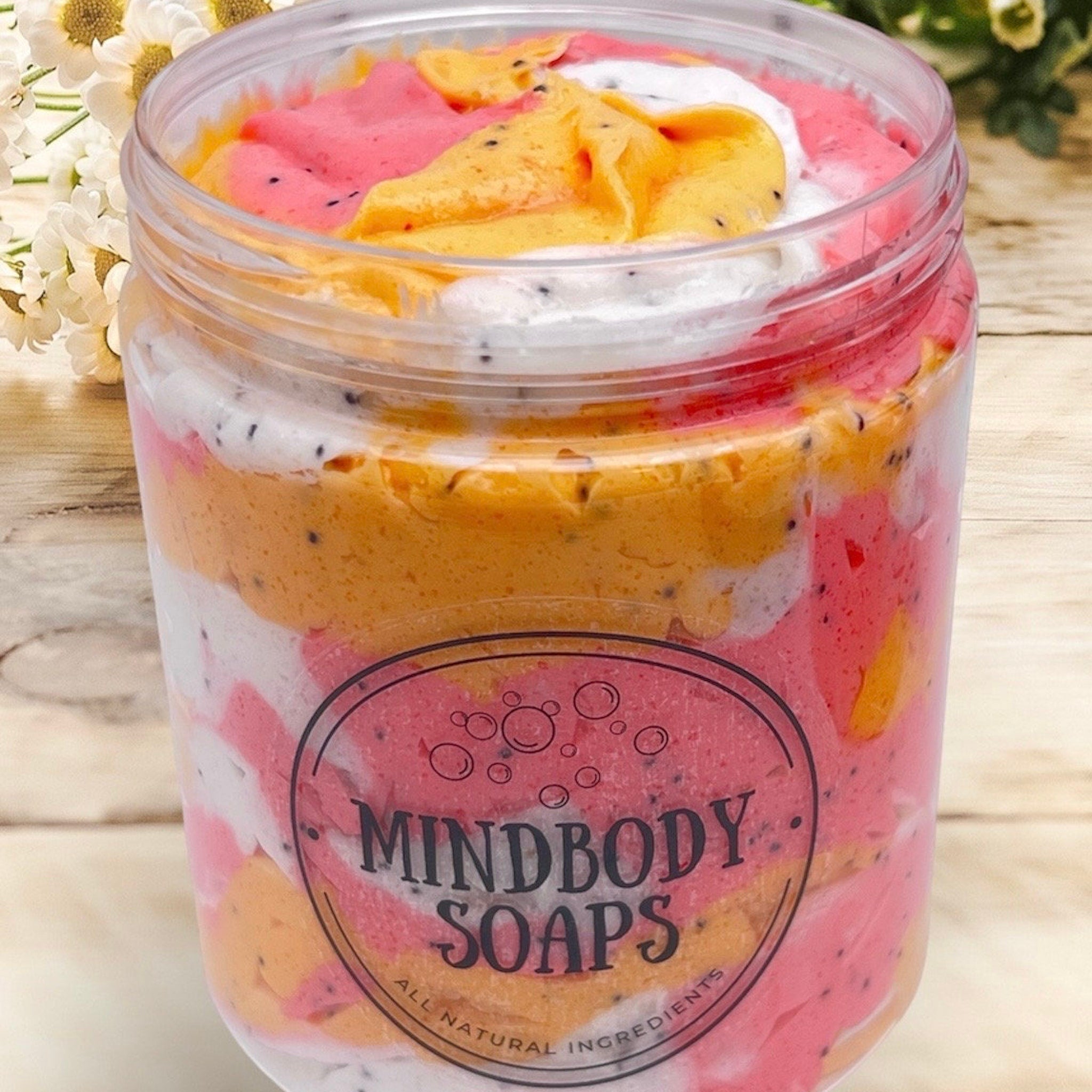 Soap jar with layered pink, orange, and white soap, with Mindbody Soaps label, in clear plastic container