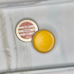 Lanolin balm in a gold tin with yellow emollient and brand name "HUE & LATHER" visible