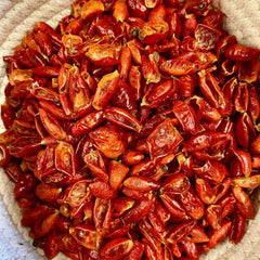 Dried red chili peppers in a woven basket with textured white and beige material