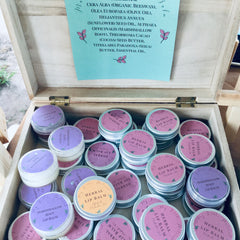 Herbal lip balm tins, silver metal, purple and pink labels, wooden box display