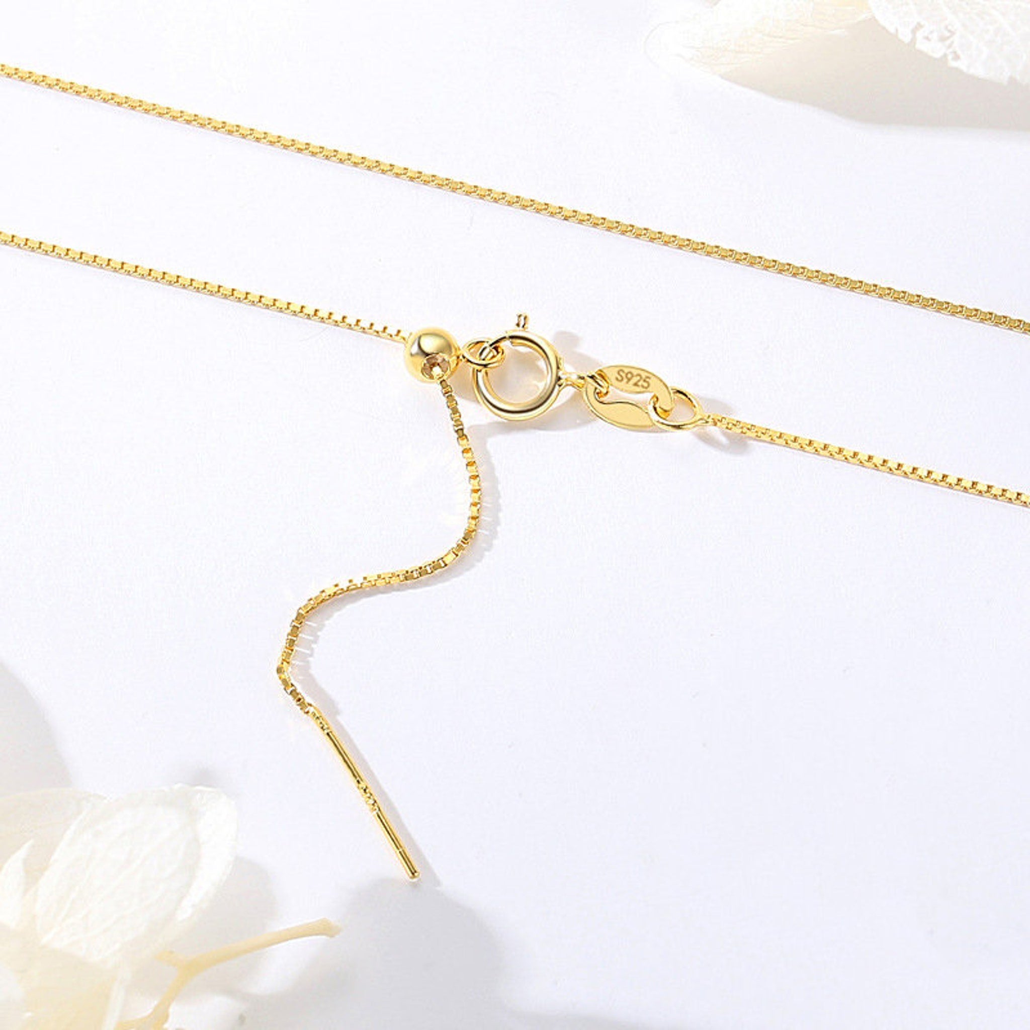 Silver and gold chain necklace displayed on a black velvet jewelry stand with reflective surface