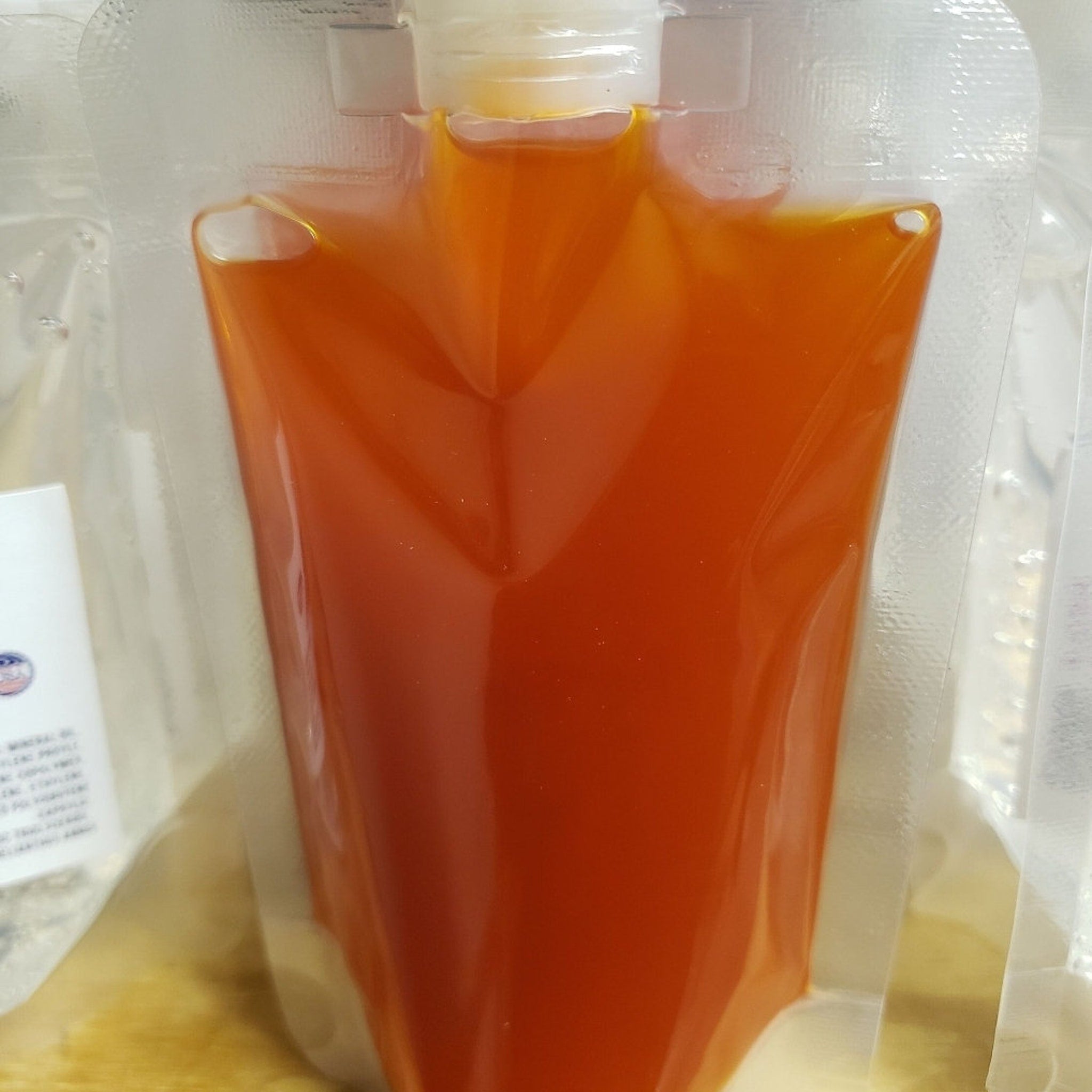 Orange liquid in clear plastic pouch with white cap and sealed edges