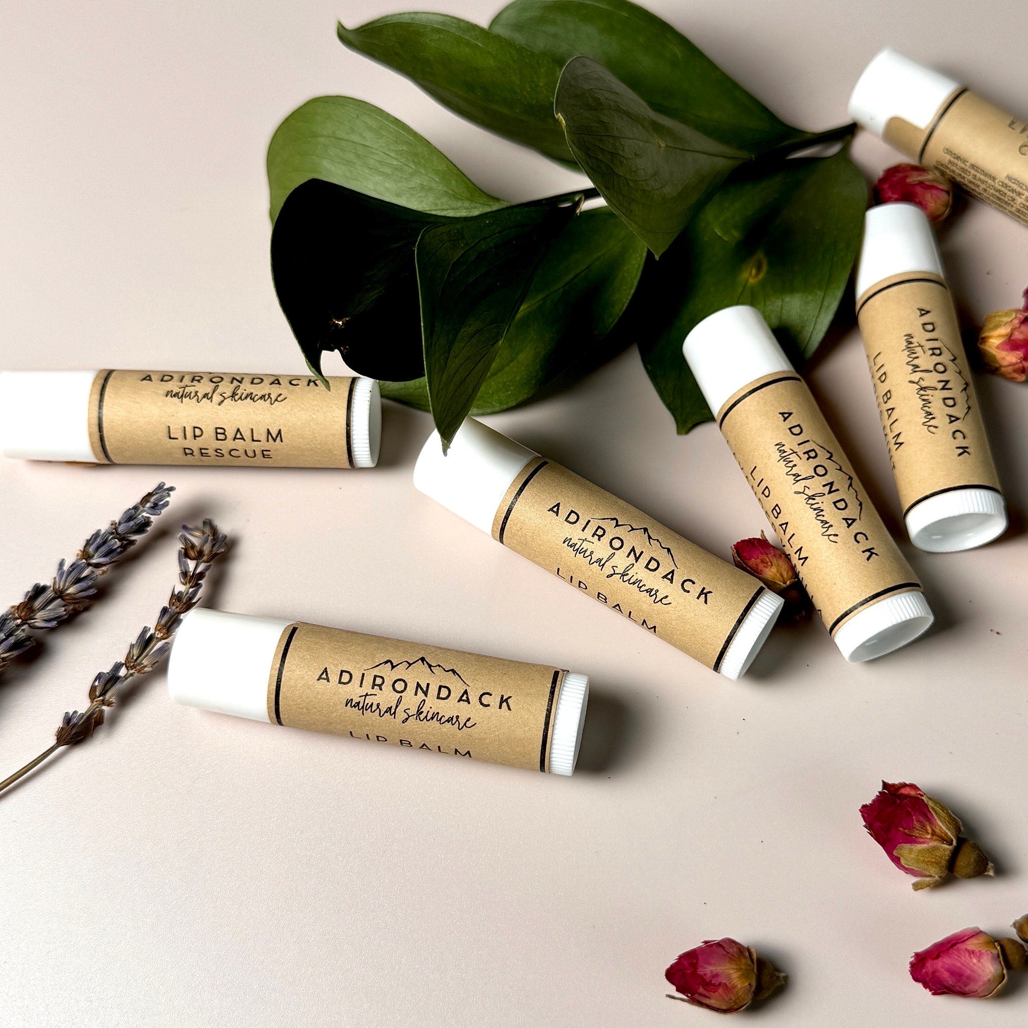 Lip balm tubes with white caps and brown labels, Adirondack Natural Skincare brand on display