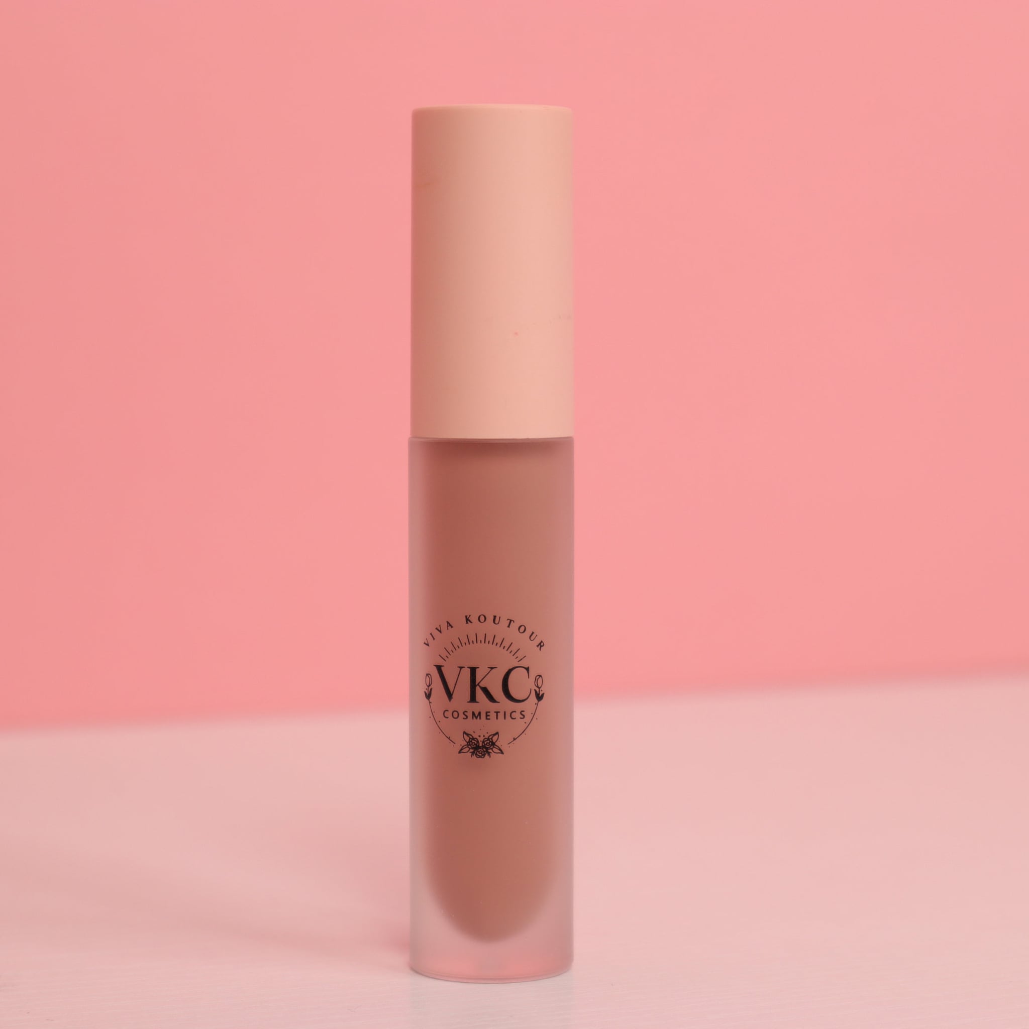 Lip gloss tube with pink cap, frosted glass, and "VKC Cosmetics" text label on the front