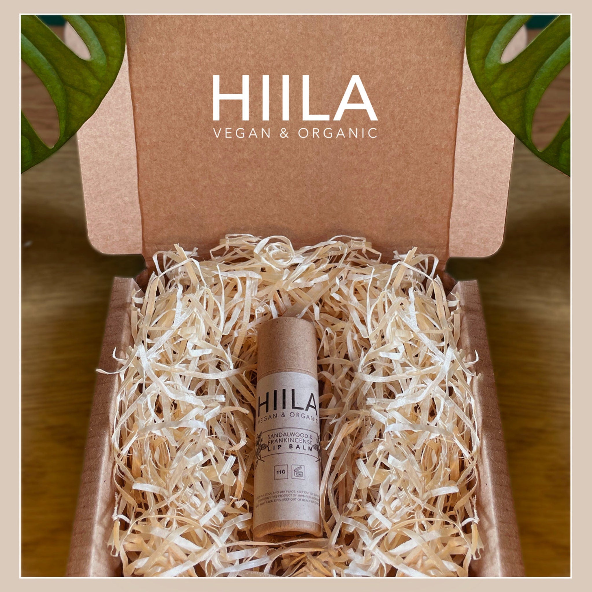Lip balm tube in cardboard packaging with shredded paper, brand name HIILA visible