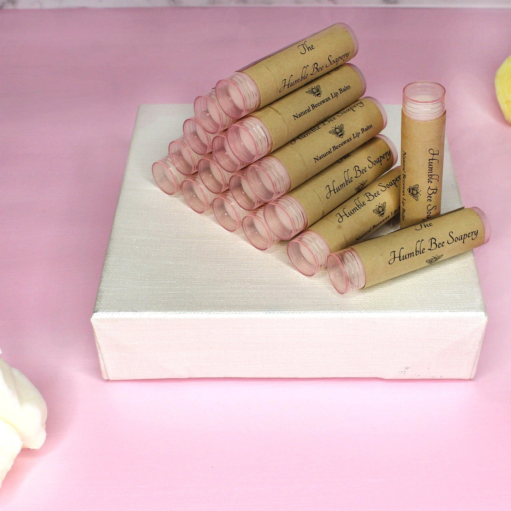 Lip balm tubes with brown paper labels, pink plastic caps, and "The Humble Bee Soapery" text